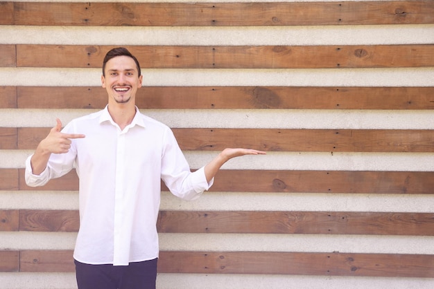 A happy European bearded guy in a white shirt holding something in the palm of his hand