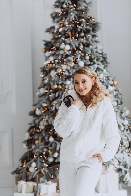 Happy european businesswoman talking on mobile phone with client at workplace with decorated Christmas tree behind smiling woman working in home office during winter holidays Soft selective focus