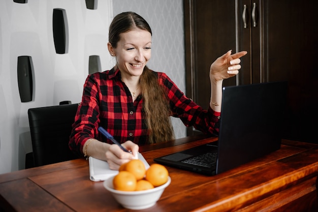 Happy european female student in casual outfit, smiling while using laptop