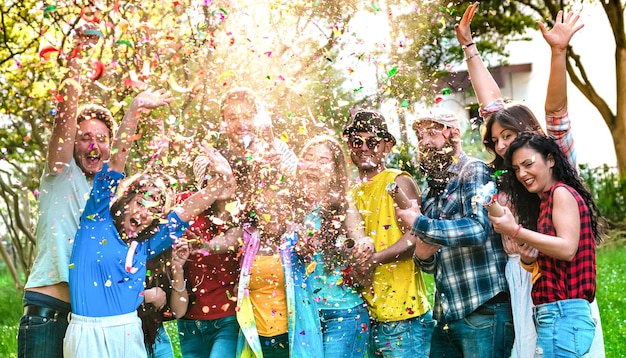 Happy excited friends having fun outdoor celebrating with confetti