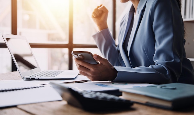 Happy excited successful business asian woman triumphing in office Portrait of a cheerful Asian businesswoman sitting at the table in office