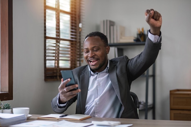 Happy excited successful businessman triumphing in office Portrait of a cheerful happy business man sitting at the laptop in office