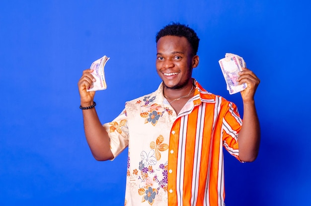 Happy and excited young african man holding bundles of cash