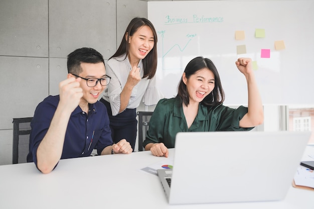 Happy excited young Asian business people celebrated success or achievement in meeting room with laptop