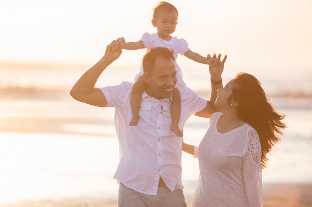 Happy family and baby enjoying sunset in the summer leisure