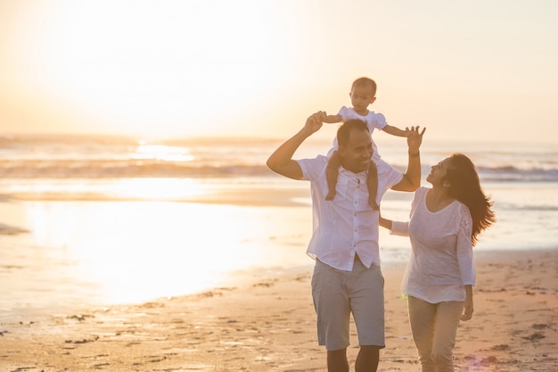 Happy family and baby enjoying sunset in the summer leisure