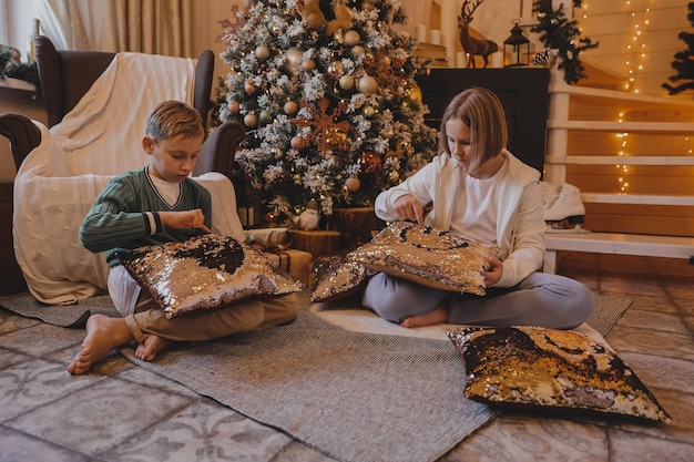 Happy family boy and girl decorating a Christmas tree with boubles and presents in the living-room, Merry Christmas and New Year Holidays. Family, winter holidays and people concept