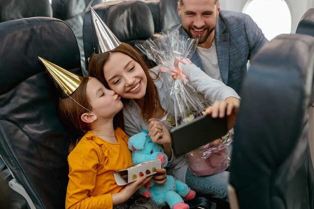 Photo happy family celebrating child birthday and making selfie in plane