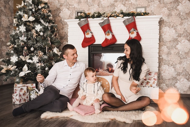 Happy family child celebrating New Year and Christmas at decorated Christmas tree and garlands