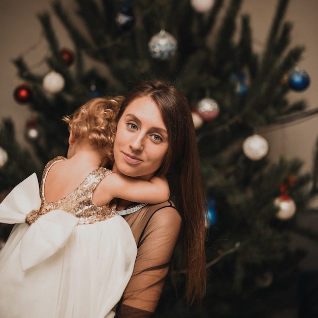 Happy family children celebrating New Year and Christmas at decorated Christmas tree and garlands