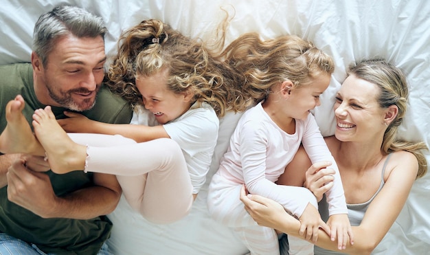 Photo happy family and children with a smile in a home bedroom bed spending quality time together young girl kids mother and man at a house with happiness and crazy fun laughing with and playing