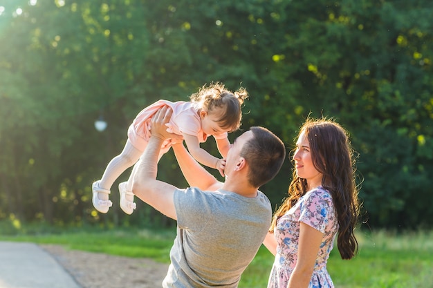 Happy family concept - father, mother and child daughter having fun and playing in nature.