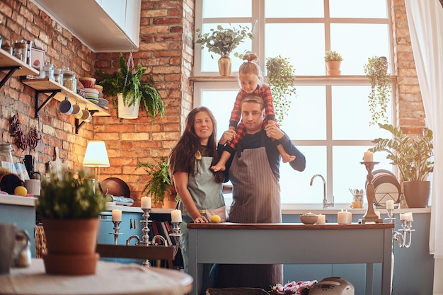 Happy family concept. Mom dad and little daughter together in loft style kitchen at morning.