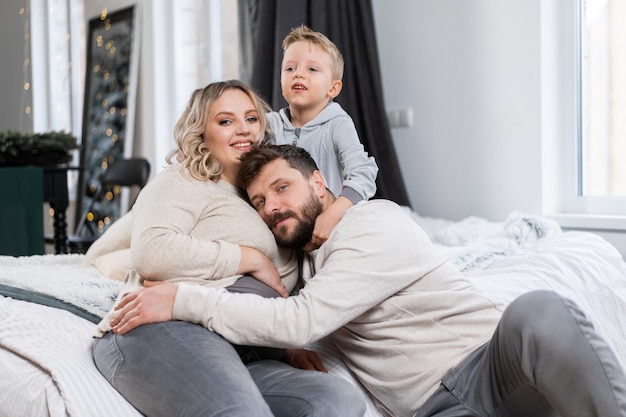 Happy family concept Mother father and little son have fun at home Caucasian family indoors Pregnant mom beard dad and funny little boy