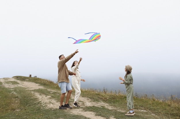 Happy family concept. parents and child are playing with a colorful kite. Young mother, father and little cute daughter having fun together outdoors in foggy day.