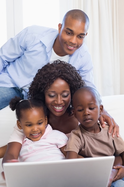 Happy family on the couch together using laptop