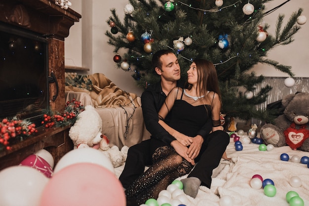 Happy family couple celebrating New Year and Christmas at decorated Christmas tree and garlands