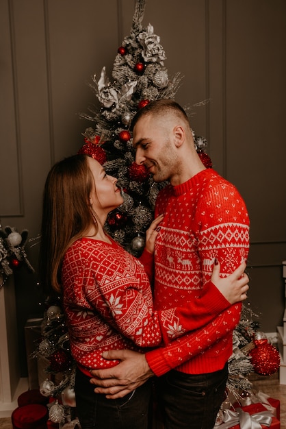 Happy family couple celebrating New Year and Christmas at decorated Christmas tree and garlands