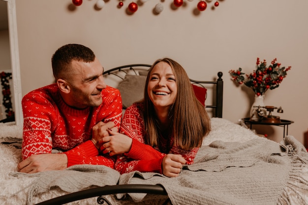 Happy family couple celebrating New Year and Christmas at decorated Christmas tree and garlands