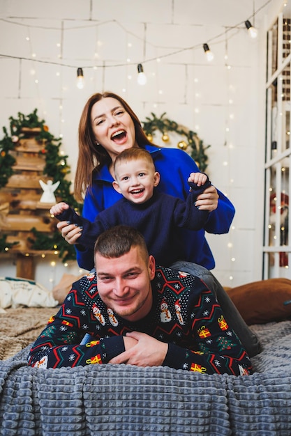 A happy family couple with a child in New Year locations New Year's festive mood in the family circle Christmas decorations in the bedroom New Year Christmas decorations at home