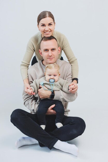 Photo a happy family couple with a child young family mom dad and little baby smiling on white isolated background loving married couple with baby