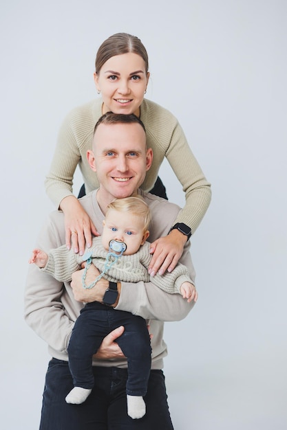 Photo a happy family couple with a child young family mom dad and little baby smiling on white isolated background loving married couple with baby