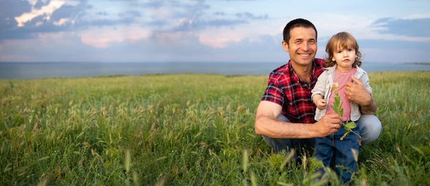 Happy family dad and son on the background of the sunset sky a man sits and holds a child Fatherhood and childhood outdoor Family lifestyle concept