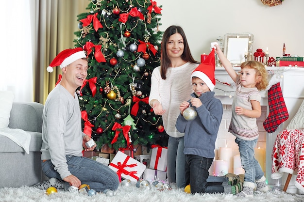 Happy family decorating Christmas tree in holiday living room