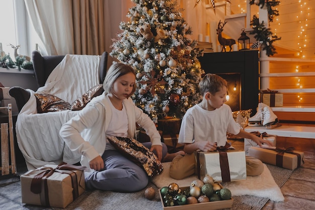 Happy family decorating a Christmas tree with boubles and presents in the living-room, Merry Christmas and New Year Holidays. Family, winter holidays and people concept