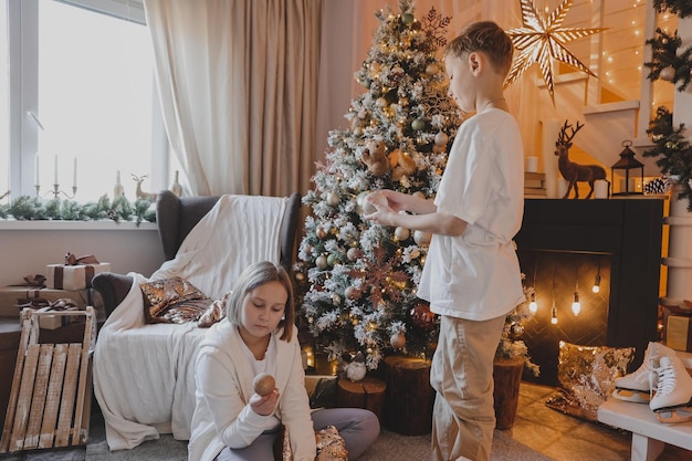 Happy family decorating a Christmas tree with boubles and presents in the living-room, Merry Christmas and New Year Holidays. Family, winter holidays and people concept