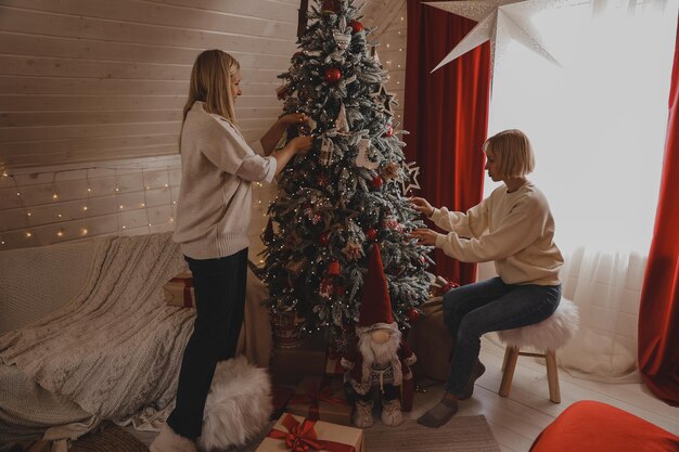 Happy family decorating a Christmas tree with boubles and presents in the living-room, Merry Christmas and New Year Holidays. Family, winter holidays and people concept