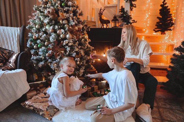 Happy family decorating a Christmas tree with boubles and presents in the living-room