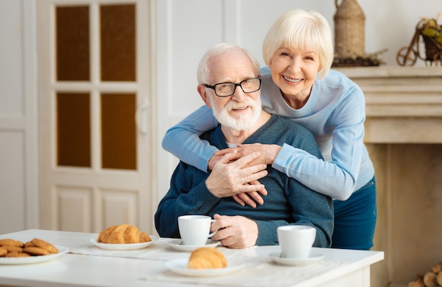 Happy family. Delighted pensioner expressing positivity while sitting at the table