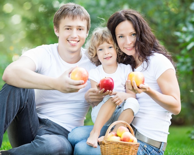 Happy family eating apples outdoors in spring park Healthy lifestyle concept