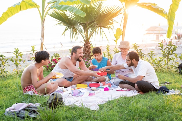 Happy family enjoying picnic on beach near sea