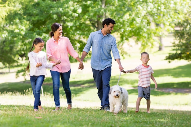 Happy family enjoying together with their pet dog in park