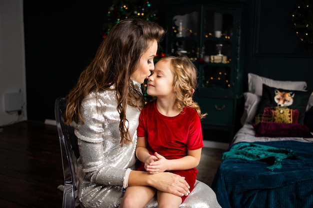 Happy family family mother and her little daughter at home near Christmas tree