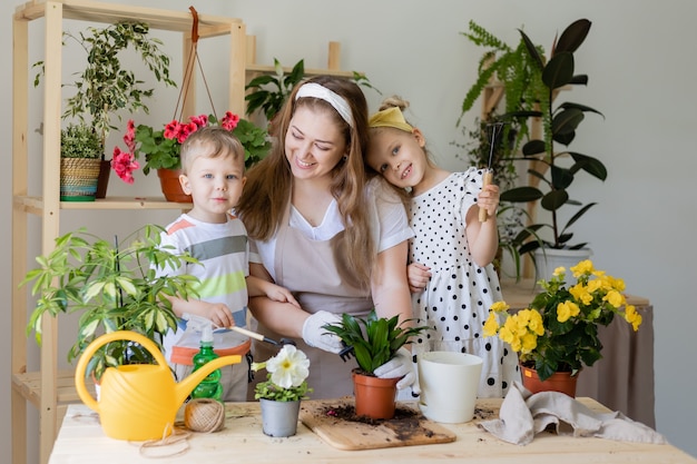 Happy family in fasting plant or transplant indoor flowers Little helper by chores home gardening