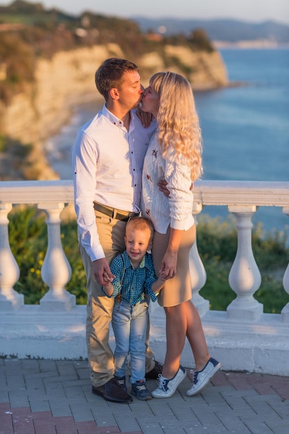 Happy family  father mother baby son walk with fun along edge of sunset sea surf on the Black Sea