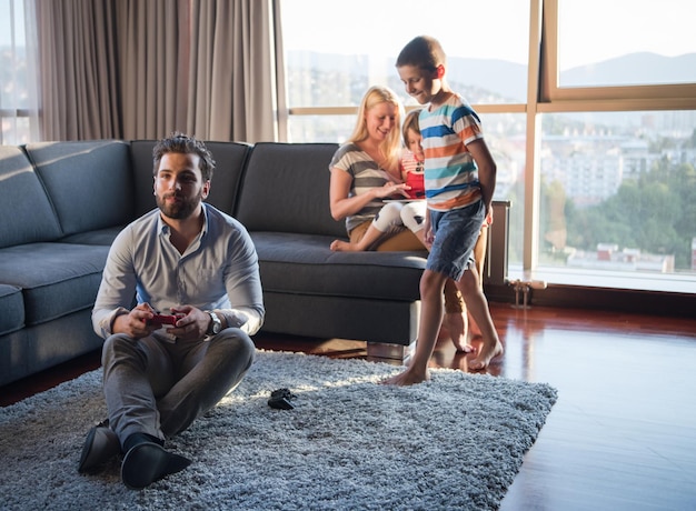 Happy family. Father, mother and children playing a video game Father and son playing video games together on the floor