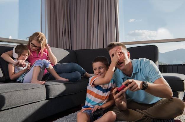 Happy family. Father, mother and children playing a video game Father and son playing video games together on the floor