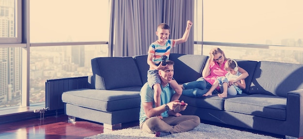 Happy family. Father, mother and children playing a video game Father and son playing video games together on the floor