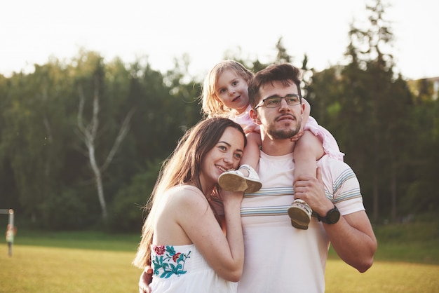 Happy family, father of mother and daughter of baby in the nature at sunset