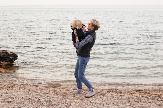 Happy family friends forever concept Smiling mother and little son playing together near sea in autumn time