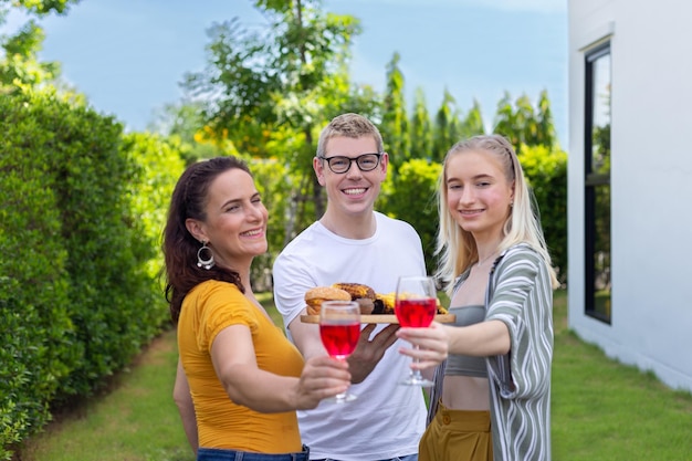 Happy family having barbecue bbq party with red wine in outdoor garden of home on holiday weekend