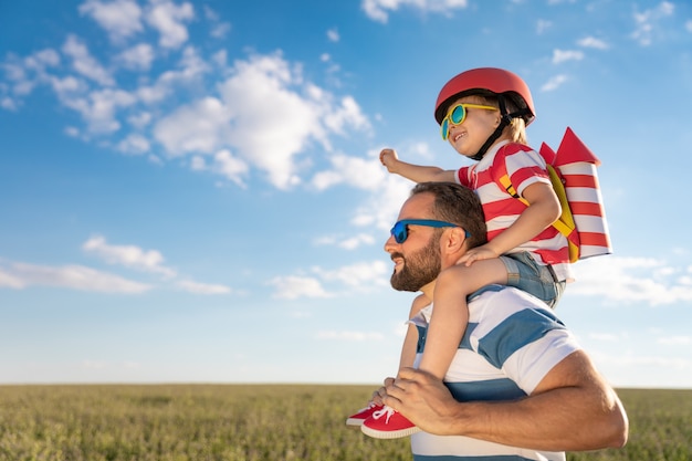 Happy family having fun outdoor. Father and son playing against blue summer sky background.