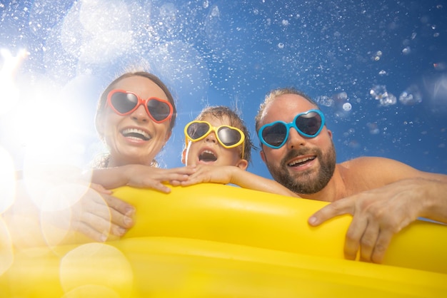 Happy family having fun on summer vacation People jumping in swimming pool against blue sky background Active holiday concept Spring break