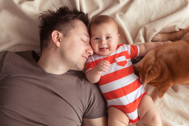 Happy family having fun with cute Shiba Inu dog. Father with his smiling baby son and Shiba Inu pet at home, top view