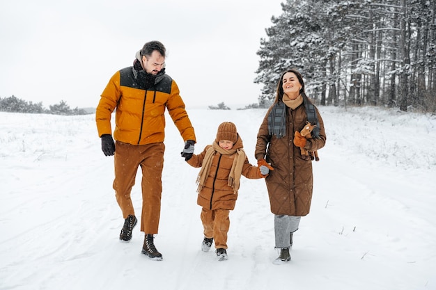 Happy family having a walk in winter outdoors in snow forest