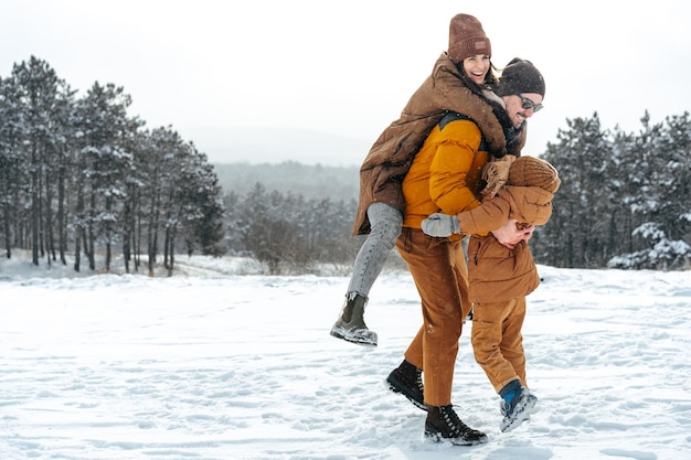 Happy family having a walk in winter outdoors in snow